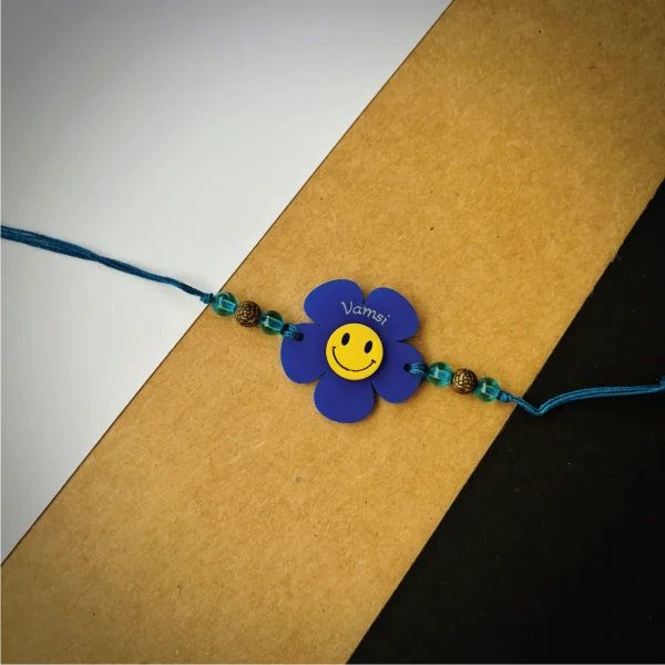 76-1-no-gift-flower-smiley-name-rakhiblue-1.webp Flower Smiley Name Rakhi Blue - Personalised Rakhi for Brother by Bubbly Decors